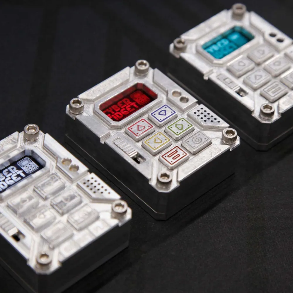 Three Cyber Fidgets in a row, their screens glowing through dark, red and teal color filters